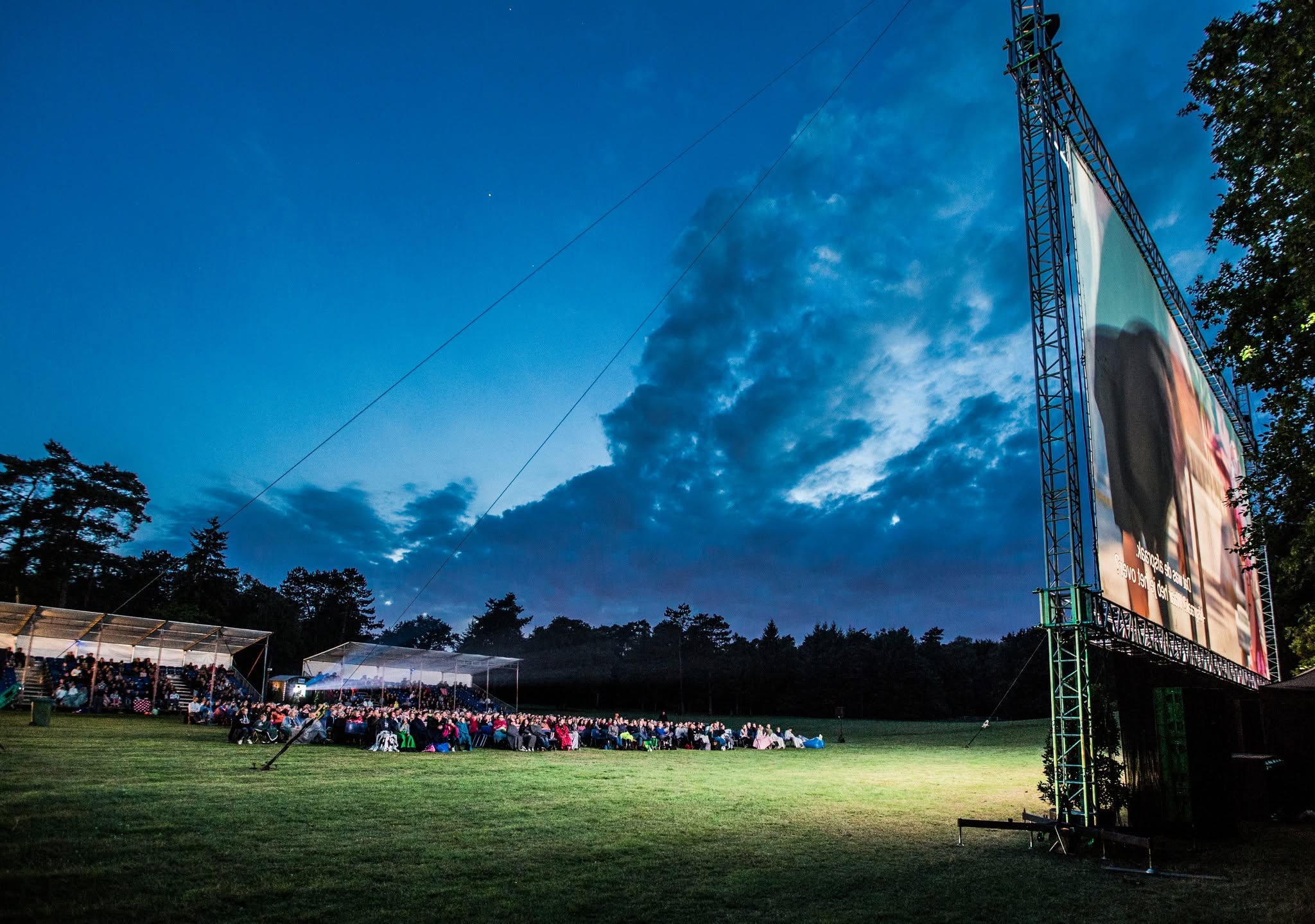 Openluchtbioscoop in het park met projectorbundel door de avondlucht