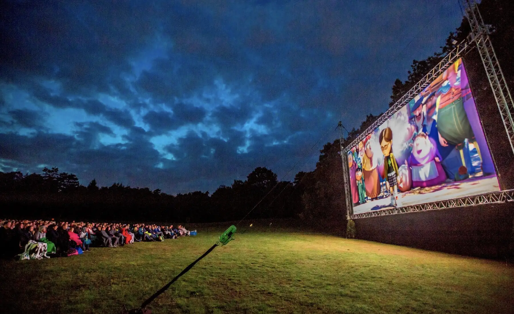 Silhouetten van bezoekers voor een verlicht openluchtscherm in de nacht